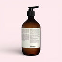 back view of Brown Aesop Resolute Hydrating Body Balm 500ml bottle with pump on a light pink background 