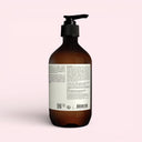 back view of Aesop Eleos Aromatique Hand Balm 500ml Brown bottle with pump and label on a pink background