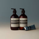 Two Aesop Reverence Aromatique Hand Balm 75ml and a tube on a gradient background
