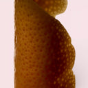 Close-up of orange peel with a light pink background