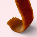 Close-up of an orange peel on a light pink background