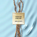 Armani Privé Les Eaux Hand Soaps Discovery Trio Gift Set's 'Vétiver d'Hiver' scent text on gold plate. A fragrance mood image with light blue background | BEAUTE KNOWS AUSTRALIA