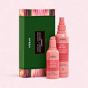 Aveda hair care products including a green box and two pink bottles on a light pink background