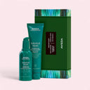 Aveda Botanical Repair™ Day & Night Strengthening Treatments Set products including a strenghthening overnight serum bottle and a tube of strenghthening leave in treatment, in front of a green packaging box with AVEDA logo and description text on a light pink background | BEAUTE KNOWS AUSTRALIA