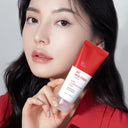 BEAUTE KNOWS Woman holding a red and white Beauty of Majesty BOM AC Red Free Cream 50ml tube against a neutral background