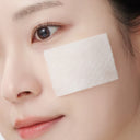 Close-up of a woman's face with white  soaked cotton pad of Beauty of Majesty BOM Hyaluronic Acid Moisture Toner  on her cheek