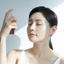 Woman applying Beauty of Majesty BOM Just One Artemisia Capillaris Extract Toner 150ml facial mist spray with a neutral background