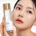 Woman holding a bottle of Beauty of Majesty BOM Peptide Power Toner 150ml close to her face.