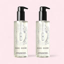 Two bottles of Bobbi Brown Soothing Cleansing Oil on a pink background