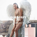 Burberry Her Elixir Eau De Parfum 100ml with a model wearing angel wings on a rooftop.