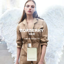 Burberry Her Eau de Toilette with a model wearing a beige trench coat against a white feathered background
