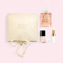 Chanel perfume set with a pink bottle, small white bottle, and yellow box on a light pink background.
