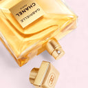 Chanel Gabrielle Essence Eau de Parfum 100ml bottle with gold cap on a light pink background