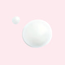Two pearly white drops of Chanel La Creme Main Hand cream on a pink background