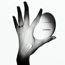 Hand holding a Chanel la creme main hand cream with a visible brand logo.