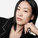 Woman wearing a black tweed garment with a white background with focus on her face