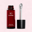 Red N°1 De Chanel Revitalizing Eye Serum 15ml serum bottle with black cap and silver applicator on a pink background