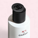 Chanel N°1 De Chanel Revitalizing Lotion 150ml bottle with black cap on a pink background