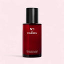 Red bottle of Chanel N°1 De Chanel Revitalizing Serum 50ml on a light pink background