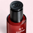 Red Chanel N°1 De Chanel Revitalizing Serum 50ml bottle with black cap on a light pink background