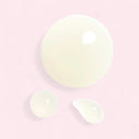 Three  translucent droplets of Chanel N°1 De Chanel Revitalizing Serum on a gradient pink background