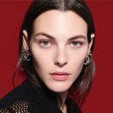 Close-up of Vittoria Ceretti wearing Chanel earrings with a red background