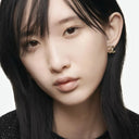 Close-up of an asian women's face, she's wearing a Chanel earring on a plain background