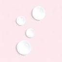Four white circular drops of Chanel N°1 De Chanel Revitalizing Lotion on a pink background