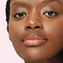 Close-up of a beautiful dark skinned woman's face with a soft pink background