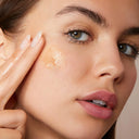 Close-up of a woman applying Clarins Double Serum Light Texture to her face