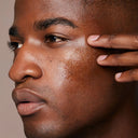 Close-up of a man applying Clarins Double Serum Light Texture to his face with a neutral background