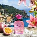Pink Dolce & Gabbana Dolce Lily Eau de Toilette 50ml perfume bottle with flowers and fruit on a scenic background
