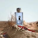 Dolce & Gabbana K perfume bottle on a desert rock with desert plants.