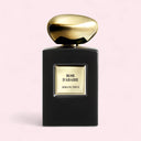 Perfume bottle with gold cap and black base on a light pink background