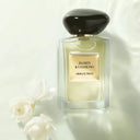 Perfume bottle labeled 'Jasmin Kusamono' by Armani Prive on a light background with flowers.