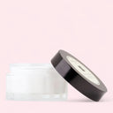 English Pear & Freesia Body Crème jar with black lid on a pink background