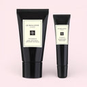 BEAUTE KNOWS A black Jo Malone London Vitamin E Hand treatment tube and a  Jo Malone London Vitamin E Lip Conditioner tubes on a light pink background