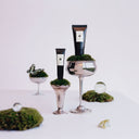 BEAUTE KNOWS Jo Malone London Vitamin E Hand  &  Lip  Travel Duo Set with moss on top of silver stands against a white background