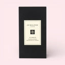 BEAUTE KNOWS Jo Malone London  Jo Malone London Vitamin E Hand &  Lip Travel Duo Set black packaging box with a white label on a light pink background