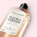 L'Occitane Cherry Blossom Fleurs de Cerisier perfumed shower gel bottle on a light pink background