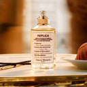 Maison Margiela Replica Afternoon Delight Eau de Toilette 100ml perfume bottle on a table with a blurred background