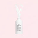 White Maison Margiela Replica Beach Walk Scented Diffuser 185ml diffuser bottle with reeds on a light pink background