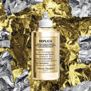 Maison Margiela Replica By the Fireplace Eau de Toilette - Limited Edition 100ml fragrance bottle on crumpled gold and silver paper background