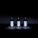 Three black Maison Margiela Replica Fantasies fragrance range bottles on a dark background