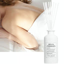 White Maison Margiela Replica Lazy Sunday Scented Diffuser 185ml diffuser bottle with reeds next to a person lying on a bed