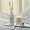 Maison Margiela Replica Lazy Sunday Scented Diffuser and candle on a bed with neutral background