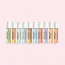 Row of Replica mini travel sized pen spray perfume bottles on a pink background