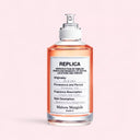 Maison Margiela Replica On A Date Eau de Toilette 100ml Perfume bottle with a label on a light pink background