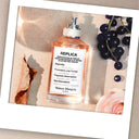 Maison Margiela Replica On A Date Eau de Toilette perfume bottle labeled 'Replica' with grapes and a flower on a textured background