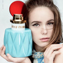 Woman holding a blue Miu Miu Eau de Parfum 50ml perfume bottle with a red cap.